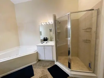 a bathroom with a shower and a tub and a sink at Ventura Village Cottage Grove Townhome in Orlando