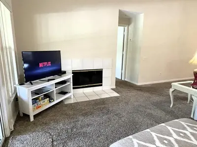 a living room with a tv on a white entertainment center at Ventura Village Cottage Grove Townhome in Orlando