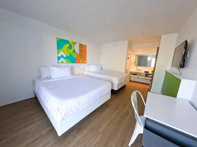 a hotel room with two beds and a flat screen tv at Impeccably cozy hotel room Developer Inn Express in Kissimmee