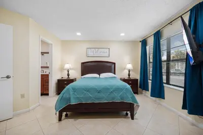 a bedroom with a bed with blue curtains and a television at 3608 Orlando Vacational 1st floor in Orlando