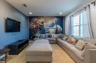 a living room with a sectional couch and a painting at Beautiful and cozy home at Sonoma Resort in Kissimmee
