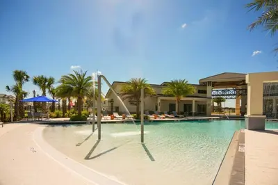 a swimming pool with palm trees and a building at Beautiful and cozy home at Sonoma Resort in Kissimmee
