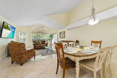 a dining room and living room with a table and chairs at Spacious Bright Close to Disney with Pool and Gym in Kissimmee