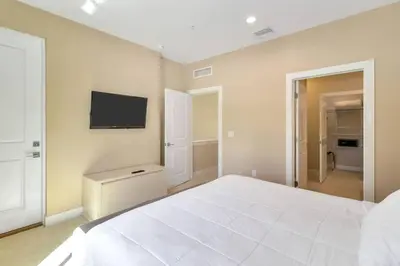 a bedroom with a large white bed and a flat screen tv at Magical Disney Home (45366427) in Orlando