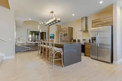 a kitchen with a island with bar stools and stainless steel appliances at Fantasy Disney Home (45858326) in Orlando