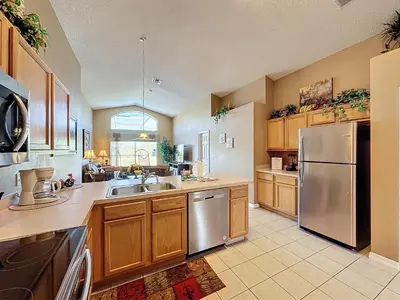 a kitchen with wooden cabinets and a stainless steel refrigerator at Four Bed in Emerald Island Resort mins to Disney in Kissimmee
