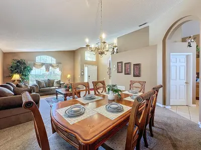 a dining room and living room with a table and chairs at Four Bed in Emerald Island Resort mins to Disney in Kissimmee