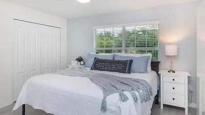 a white bedroom with a bed with blue pillows and a window at City Palm Villa in Orlando