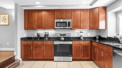 a kitchen with wooden cabinets and a microwave at Sunny Summer Stay - Renovated TownHome by Disney! in Orlando