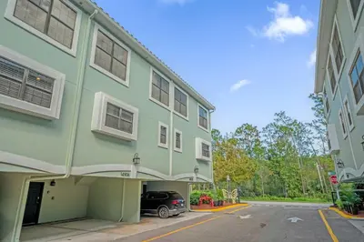 a green building with a car parked in a parking lot at Family Summer Trip - Renovated TownHome by Disney! in Orlando