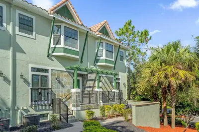 a green house with a palm tree in front of it at Family Summer Trip - Renovated TownHome by Disney! in Orlando