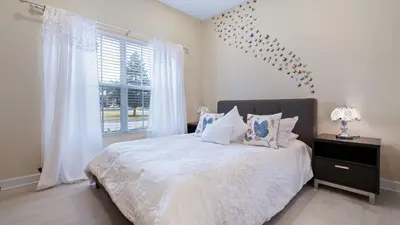 a bedroom with a bed with white sheets and a window at Paradise Pines Villa in Orlando