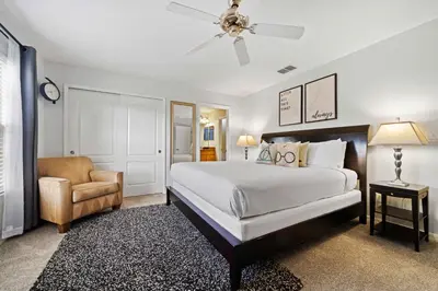 a bedroom with a bed and a chair and a ceiling fan at 8953 Candy Palm Road in Kissimmee
