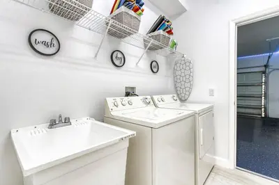 a white laundry room with a sink and a washing machine at Stunning 5 bedroom pool home in gated community minutes from Disney in Kissimmee