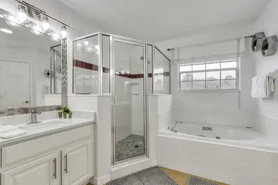 a white bathroom with a tub and a shower at Stunning 5 bedroom pool home in gated community minutes from Disney in Kissimmee