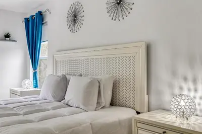a white bedroom with a bed with white pillows at Stunning 5 bedroom pool home in gated community minutes from Disney in Kissimmee