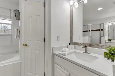 a white bathroom with a sink and a mirror at Stunning 5 bedroom pool home in gated community minutes from Disney in Kissimmee