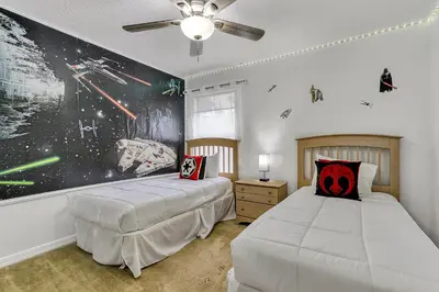 a bedroom with two beds and a painting on the wall at Stunning 5 bedroom pool home in gated community minutes from Disney in Kissimmee
