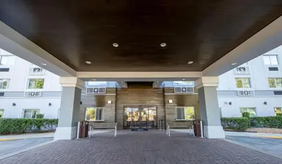 a large building with two benches in front of it at Holiday Inn Express & Suites Clermont SE - West Orlando by IHG in Orlando
