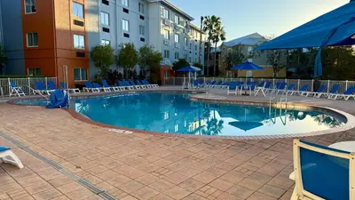 a swimming pool with blue chairs and a hotel at Holiday Inn Express & Suites Clermont SE - West Orlando by IHG in Orlando