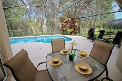 a table and chairs in a greenhouse next to a pool at Gorgeous 4 Bed Home In Gated Community in Kissimmee