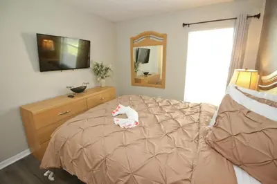 a bedroom with a bed with a dresser and a mirror at Newly Renovated Home With Calming Atmosphere in Kissimmee