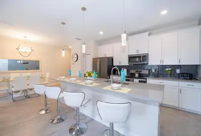 a large kitchen with white cabinets and white chairs at 5011CL TOWNHOME 4 BEDS 3 BATHS FREE WATERPARK in Kissimmee