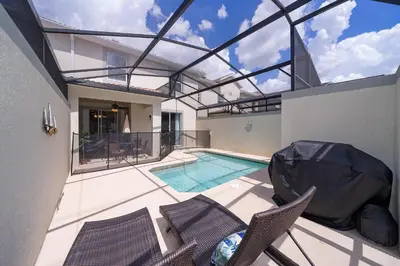 a house with a swimming pool and some chairs at 5011CL TOWNHOME 4 BEDS 3 BATHS FREE WATERPARK in Kissimmee