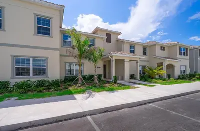 a large house with a palm tree in the driveway at 5011CL TOWNHOME 4 BEDS 3 BATHS FREE WATERPARK in Kissimmee