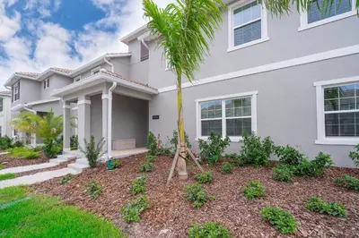 a house with a palm tree in the front yard at 4816LN TOWNHOUSE 4 BEDROOMS 3 BATHROOMS PRIVATE POOL in Kissimmee