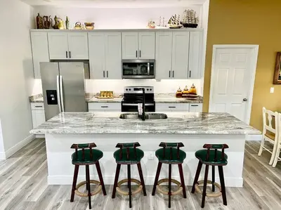 a kitchen with a counter with four green bar stools at Sanford's Seahaven in Sanford