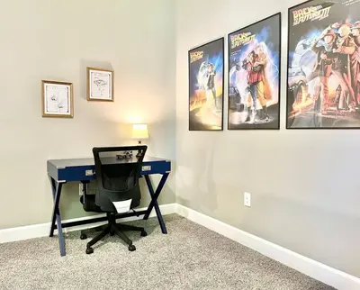 a desk in a room with posters on the wall at The Arcade close to downtown with fenced yard in Sanford
