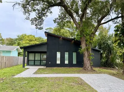 a black house with a tree in front of it at The Butterfly House - with sauna in Sanford