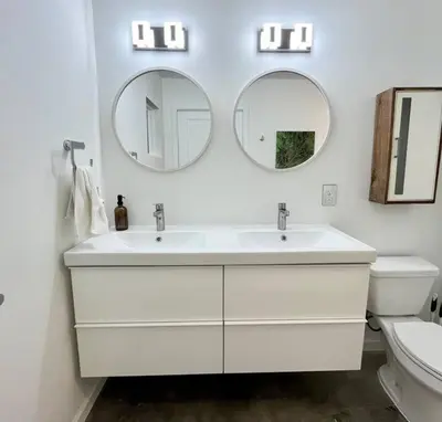 a bathroom with two sinks and a toilet and two mirrors at The Butterfly House - with sauna in Sanford
