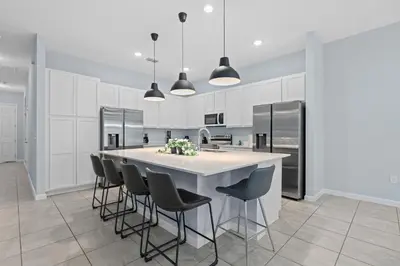 a kitchen with white cabinets and a large island with chairs at Cozy Master Room with Private Bath in Kissimmee
