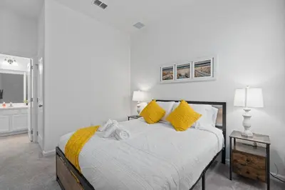 a white bedroom with a bed with yellow pillows at Cozy Master Room with Private Bath in Kissimmee