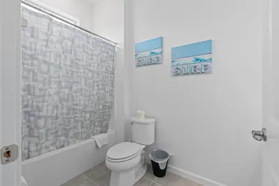 a bathroom with a toilet and two pictures on the wall at Cozy Master Room with Private Bath in Kissimmee