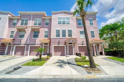 a pink house with a palm tree in front of it at The Epic Colorado Vista Cay Orlando in Orlando