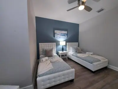 two beds in a room with a blue wall at Serenity Close to Disney Orlando in Orlando