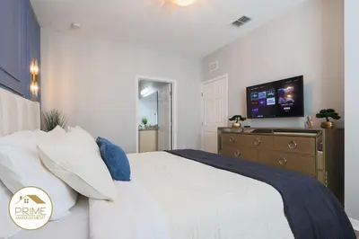 a bedroom with a bed with a tv on the wall at NEW Renewed 3BD Modern 10 Min to Disney in Kissimmee