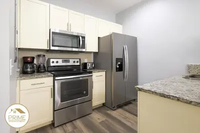 a kitchen with stainless steel appliances and white cabinets at NEW Renewed 3BD Modern 10 Min to Disney in Kissimmee