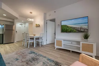 a kitchen and dining room with a table and a television on a wall at Pool view apartment near Epic Universe and Universal Studios in Orlando