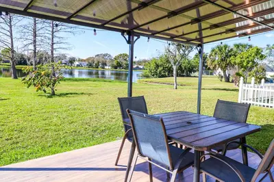 a wooden table and chairs on a deck with a lake at BRANDNEW 2023 LAKEFRONT APT in Kissimmee