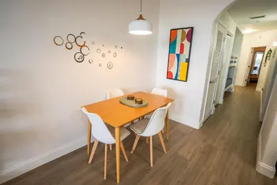 a dining room with a wooden table and white chairs at Orlando 4th Floor - 5 min Disney in Orlando