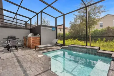 a swimming pool with a patio with a table and a grill at Themed Home Near Disney with Pool in Kissimmee