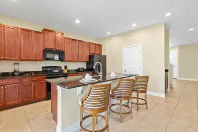 a large kitchen with wooden cabinets and bar stools at Encore Resort 5 Bedroom Home with Pool 2403 in Orlando