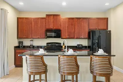 a kitchen with wooden cabinets and bar stools at Encore Resort 5 Bedroom Home with Pool 2403 in Orlando
