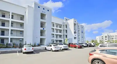 a parking lot with cars parked in front of a building at 3BE&2BA Apartment at Storey Lake Resort 59 in Kissimmee