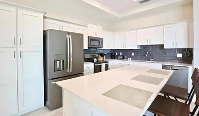 a kitchen with white cabinets and a stainless steel refrigerator at 3BE&2BA Apartment at Storey Lake Resort 59 in Kissimmee