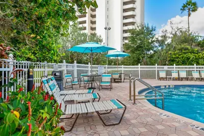 a pool with chairs and tables and umbrellas next to a building at 2 suites ground floor apartment near Intern Drive in Orlando